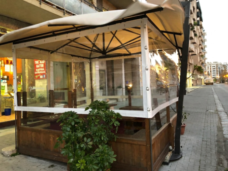 Dehors di bar con pergola e tende da sole personalizzate sulla vetrina